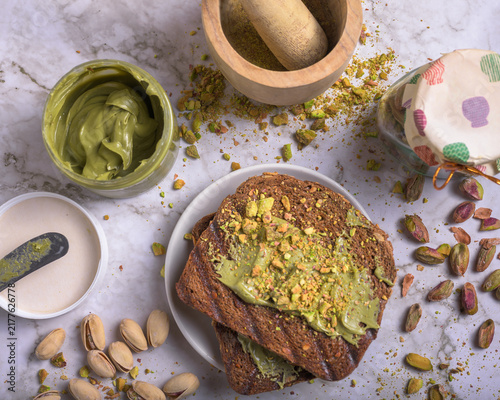 Fotografie Two slices of toasted artisan bread spread with smooth pistachio cream and sprin