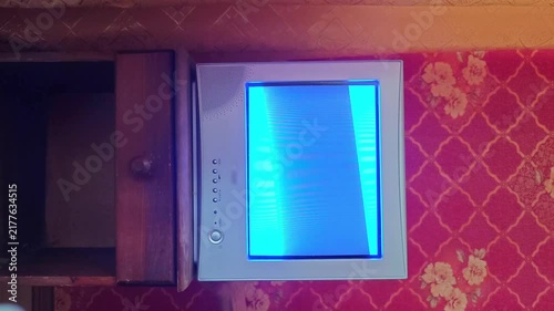 Old monitor shows blue screen while placed on a wooden table near the wall