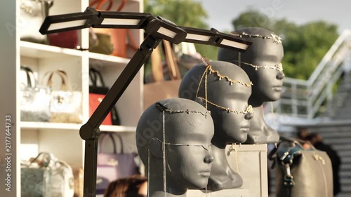 Mannequin heads displaying intricate jewelry and luxury fashion accessories at market stall