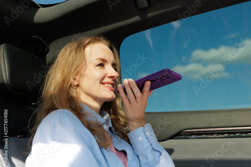 Businesswoman using smartphone voice assistant while riding in car