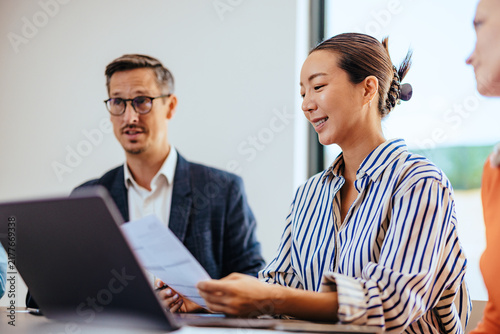 Smiling Colleagues Discuss Documents and Strategy During a Business Meeting in a Modern Office
