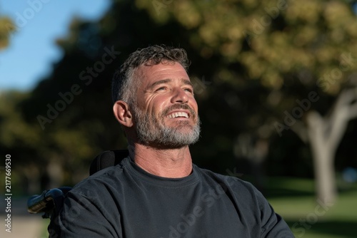 Adult man in power wheelchair looking up outdoors with sunlight