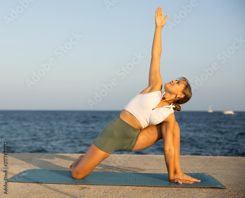 Foto Professional girl doing yoga near sea, on embankment she fulfil various asana si