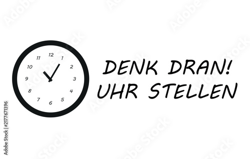 a clock on the wall with a message in German reminding you to set the clock.