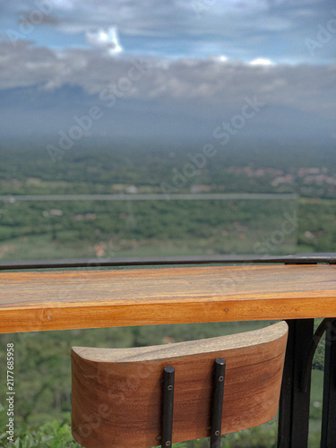 Cuadro en lienzo Wooden Table and Chair with Mountain and Cloudy Sky