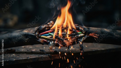 Cuadro en lienzo A close-up view of a damaged electrical cable burning and melting, with visible wires sparking and smoke rising, highlighting a hazardous electrical short circuit