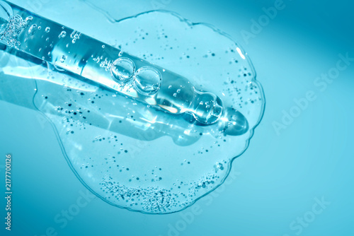 Pipette dripping transparent blue serum gel with bubbles