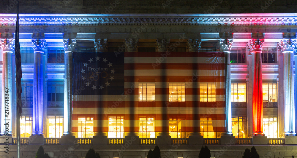 Obraz premium Building facade with patriotic lights. Building exterior displays freedom banner. Federal architecture frames building flag. Night celebration illuminates building columns.