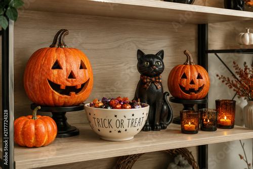 Seasonal shelf display with pumpkins, candy bowl, and cat figurine, autumn retail decor