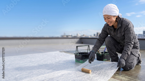 Fototapeta kuchenna 屋上でローラーを使って防水シートを施工する女性職人