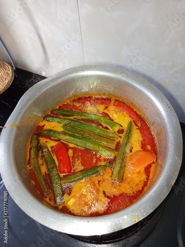 Foto Homemade Asian sour and spicy stew with fish slices, green ladyfingers, and red