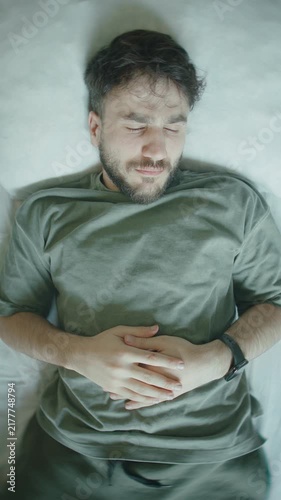 Man in bed checking smartwatch realizing he overslept, shocked reaction close-up ,vertical video