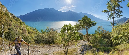 Hiker on the western shore of Lake Garda with the mountain range Monte Baldo, Limone Sul Garda, Brescia, Lake Garda West, Lombardy, Italy