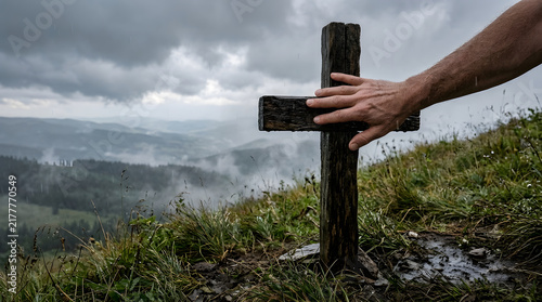 Hand Resting on a Weathered Wooden Cross Overlooking a Misty Mountain Landscape Reflecting Faith and Reflection