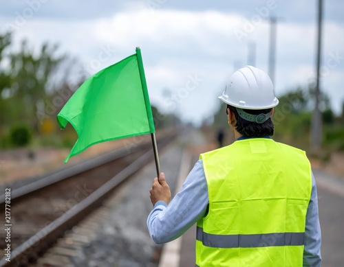 Safety Personnel Waving Green Flag at Railway Track to Signal Clear Path for Train Operation