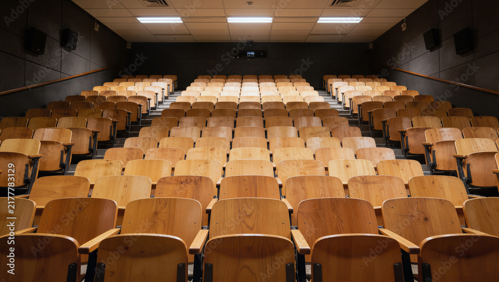 Fototapeta premium Tiered wooden lecture hall with rows of chairs in ascending formation, empty academic venue