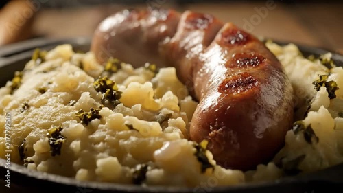 Close-up of Traditional Bangers and Mash with Grilled Sausage Served on Creamy Mashed Potatoes Mixed with Greens (Colcannon or Kale) in a Rustic Setting