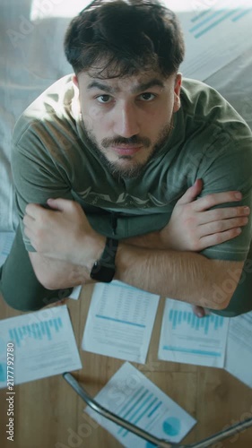 Exhausted Freelancer Sitting on Bed Looking Up at Camera Surrounded by Financial Charts and Laptop ,vertical video