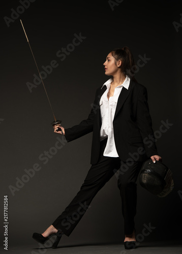 Canvastavla beautiful brunette in a black suit and white shirt in heels with a rapier and he