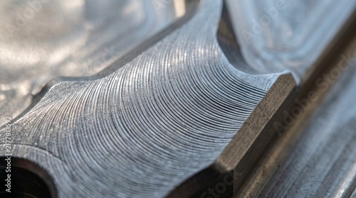 Macro photograph of precision CNC machined titanium metal surface showing fine curved tool path grooves
