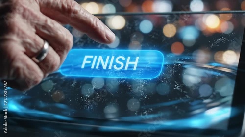 A close-up of an elderly hand pressing a glowing blue 'FINISH' button on a futuristic digital interface with blurred background lights.
