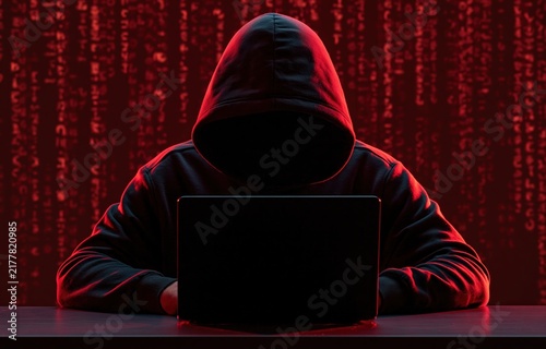 Obraz na płótnie Hacker in a hoodie using a laptop to commit cybercrime with digital binary code and internet security technology