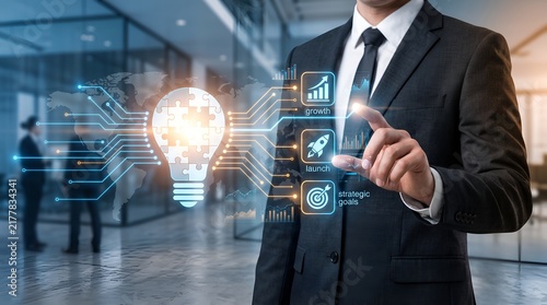 Businessman touching glowing lightbulb puzzle and business strategy icons