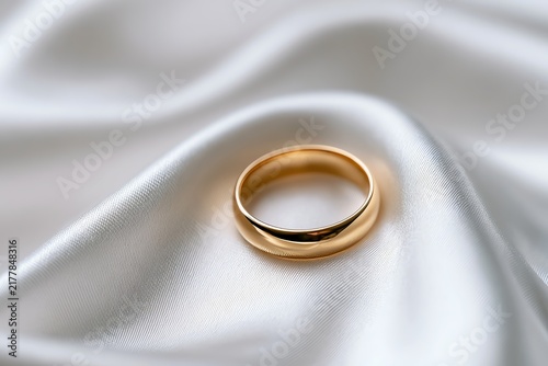Elegant gold ring on soft satin fabric.