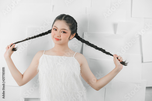 Фотография Teenage Girl Holding Long Braided Pigtails Indoors.