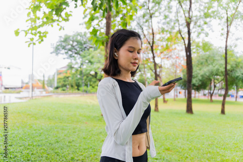 Foto Asian sporty woman open speakerphone talking with friend on smartphone in public