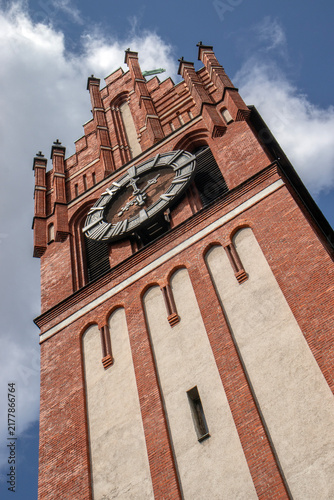 Bild auf Leinwand Historic red brick clock tower viewed from below against a bright blue sky with