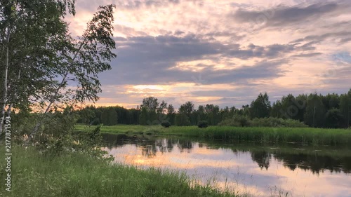 Scenic summer river with glowing sunset sky reflected on calm water natural landscape