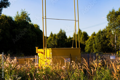 Quadro su tela Bright yellow gas distribution station standing in a wild field surrounded by lu