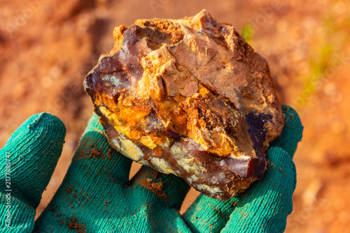 Photography Close-up of a raw flint stone with vibrant chalcedony inclusions held in a glove