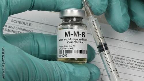 Healthcare professional wearing green medical gloves holding an mmr vaccine vial and filled syringe with medicine