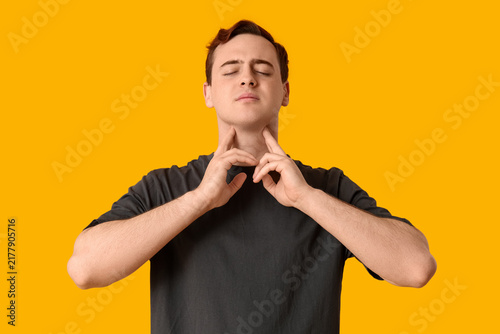 Foto Young man with sore throat on yellow background