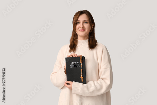 Konstfotografi Religious young woman with Holy Bible and rosary beads on white background