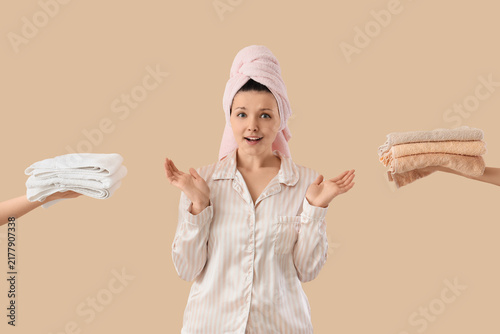 Shocked young woman receiving towels after shower on beige background
