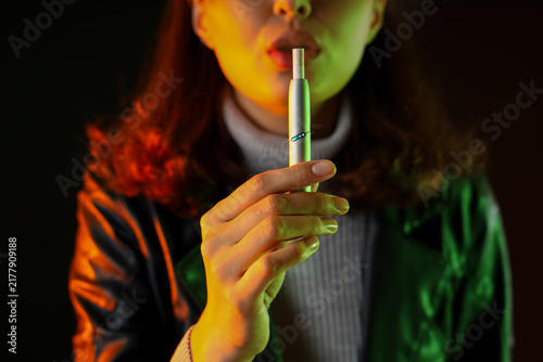 Quadro su tela Young woman smoking electronic cigar on dark background, closeup
