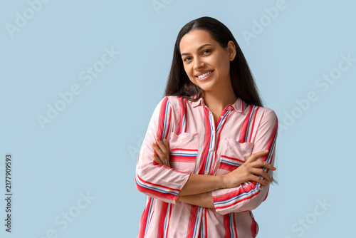 Cheerful young woman with crossed arms on blue background