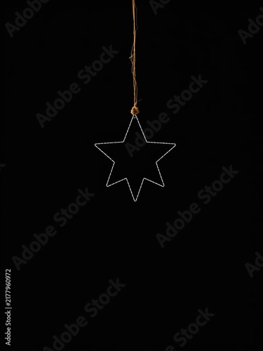 Silhouette of a star suspended by a single thread against a black background, delicate and ethereal, ||black, motif