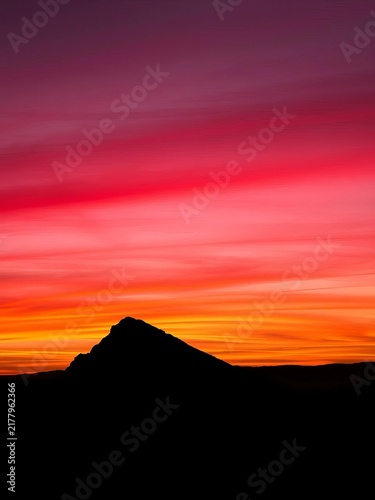 Slope silhouetted against vibrant orange-pink sky, ||mountain, recreation