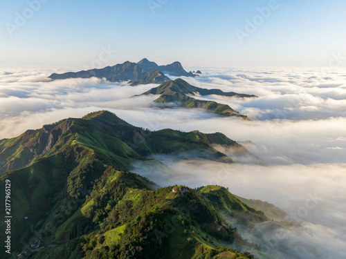 Green mountains rising above a sea of clouds at sunrise