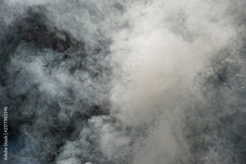 Fotografía A close-up image of thick white smoke rising, billowing, and swirling unpredictably against a dark, shadowy background, creating a dramatic and abstract texture