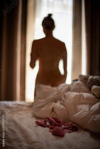 Woman standing by the window at a hotel room one early morning