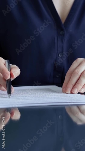 Woman's hand signing a document with a pen, confirming a business agreement, making a legal commitment, completing official paperwork, and taking a crucial step in administrative processes