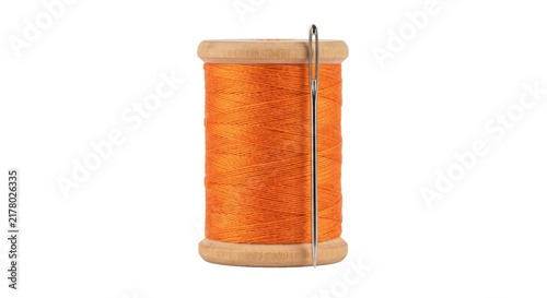 Fotografía Bright orange thread on a wooden spool with a sewing needle inserted