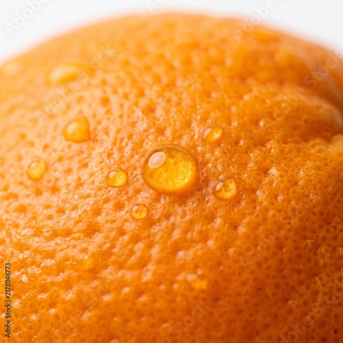 Macro photography of fresh orange fruit peel showing texture with water droplets on skin.