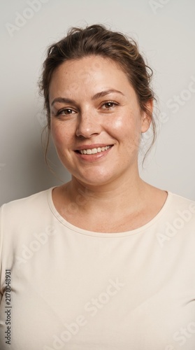 Close-up portrait of a smiling mid-adult woman with natural makeup looking at the camera.