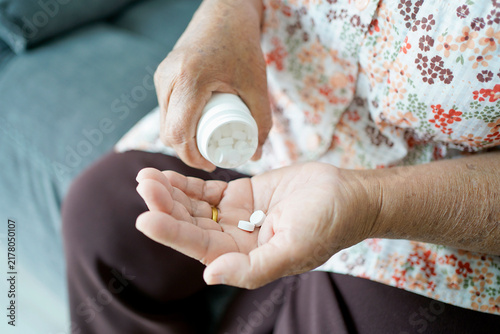Asian older elderly woman pouring medicine on hand. Healthy lifestyle.